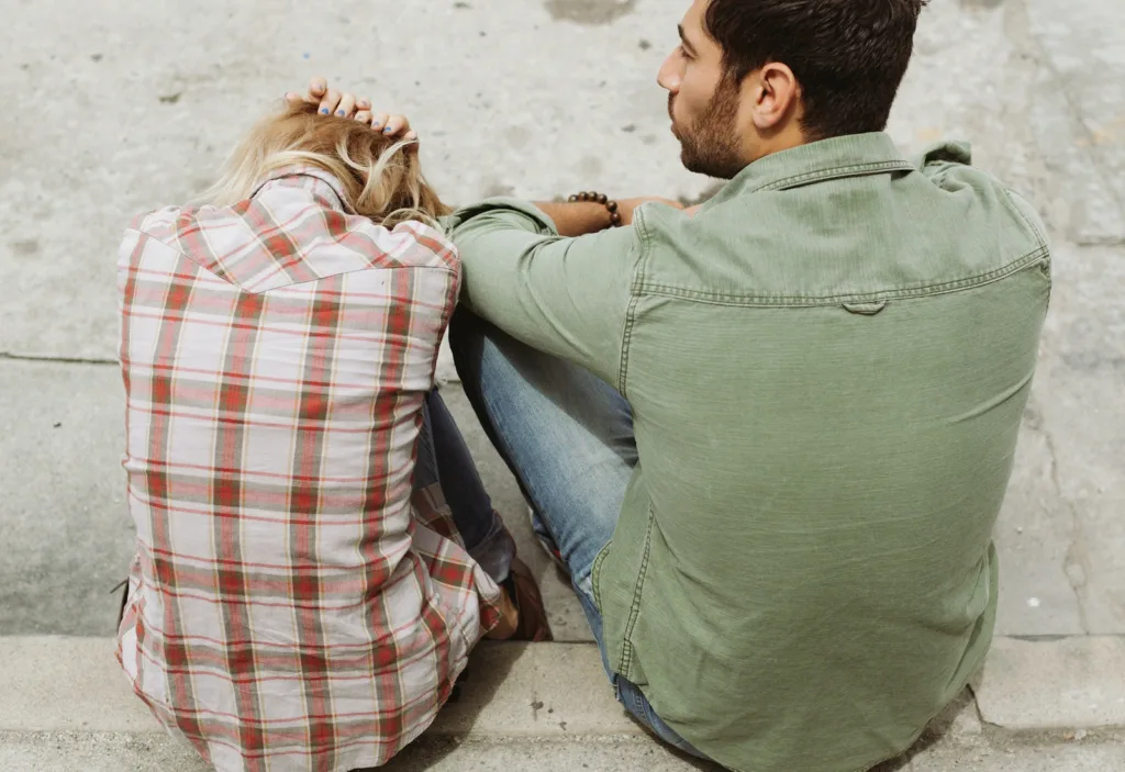 Man and Woman Sitting on Sidewalk. What to when a man pulls away and understanding his need for independence