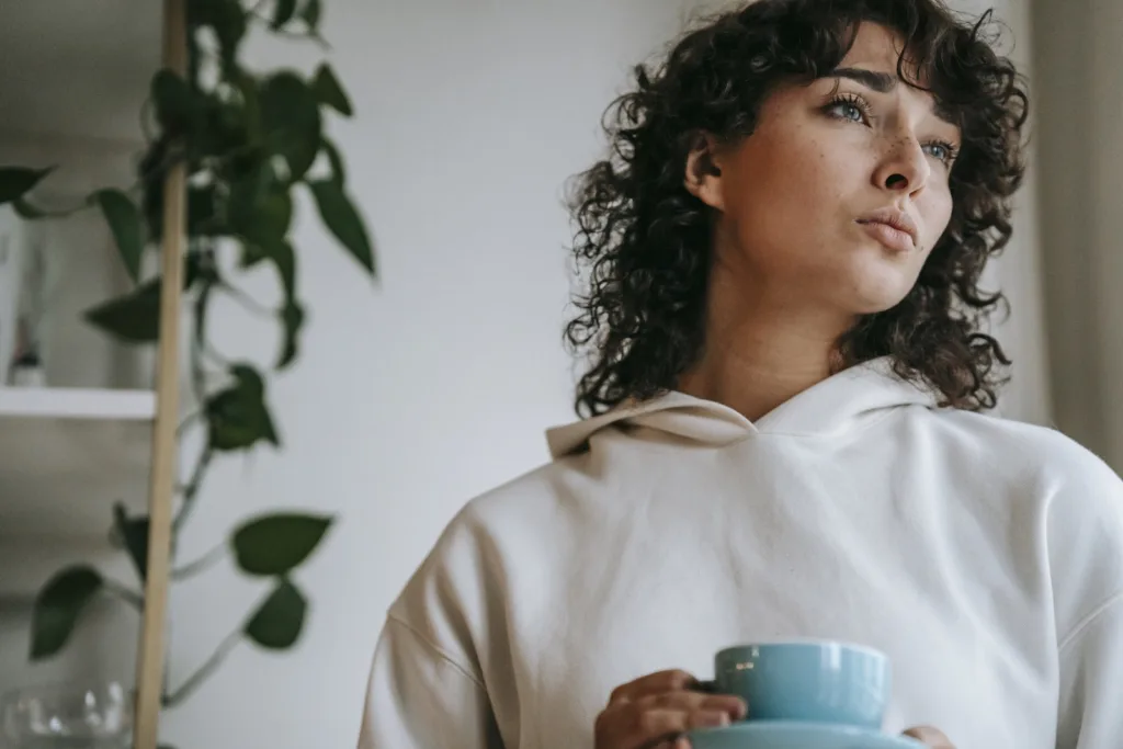 Pensive woman with hot beverage at home trying to overcome nervousness. Confidently connect with your crush to conquer nerves.