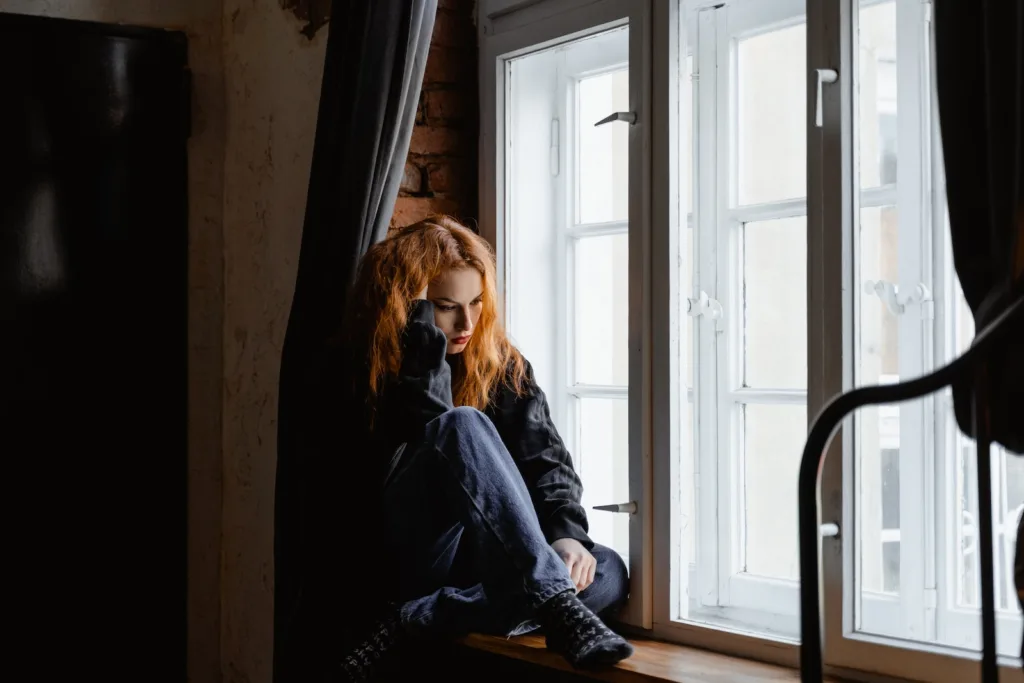 Woman in Black Leather Jacket Sitting on Brown Wooden Floor. emotional dependency can be some toxic relationship traits and damaging habits.