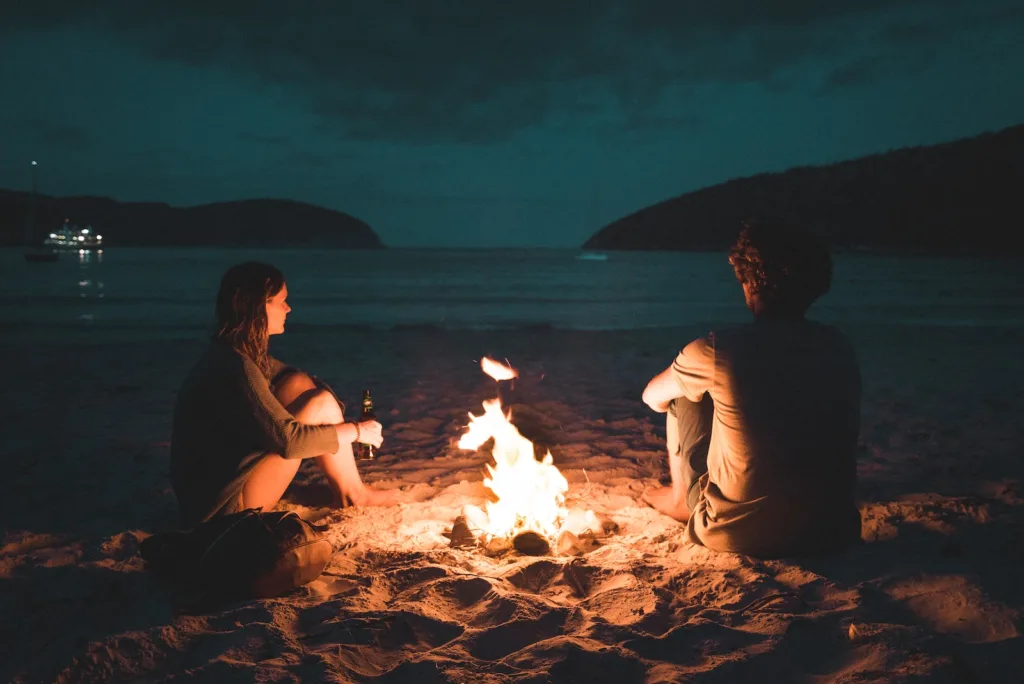 man and woman with bone fire sitting on seashore decode his hesitation and why he won't ask you out.