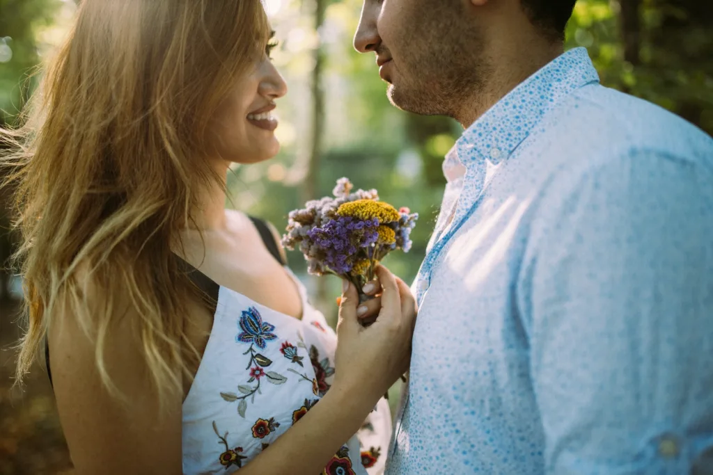 man and woman facing each other while holding flowers. Risks of instant attraction and instant spark.