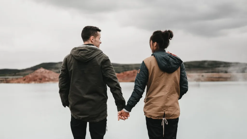 couple holding hand front of body of calm water with mountain distancedivorce, separation, argument. will taking a break in a relationship rekindle your love?
