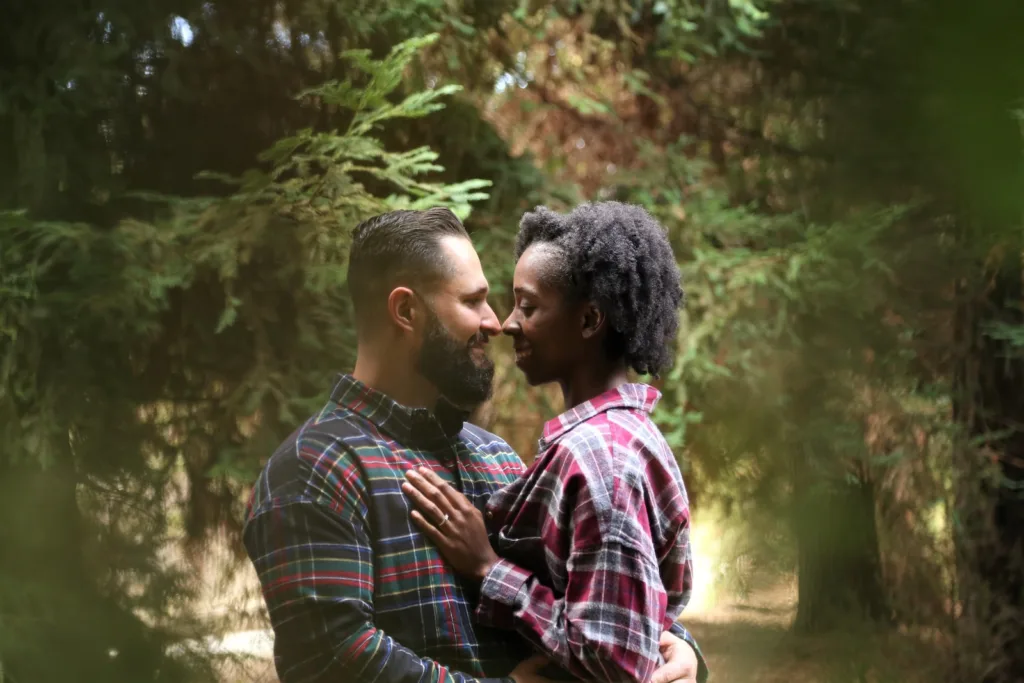 man and woman in interracial relationships wearing button-up sports shirt on the center of trees
