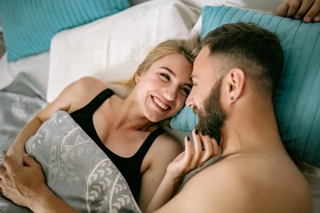 Happy Couple Cuddling in Bed. Can you rekindle your relationship through communication and meaningful conversations? Learn how to reignite the spark.