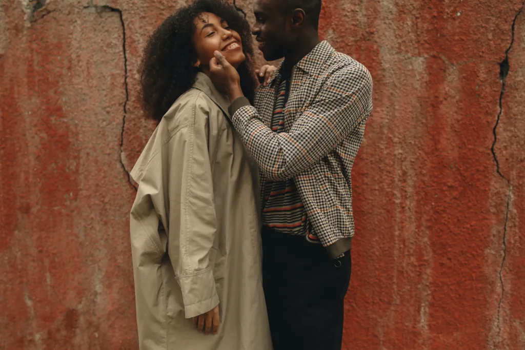 Happy Couple Standing Near A Red Wall - 5 Ways to Avoid Culture Clash in Interracial Relationships - Intercultural, Traditions