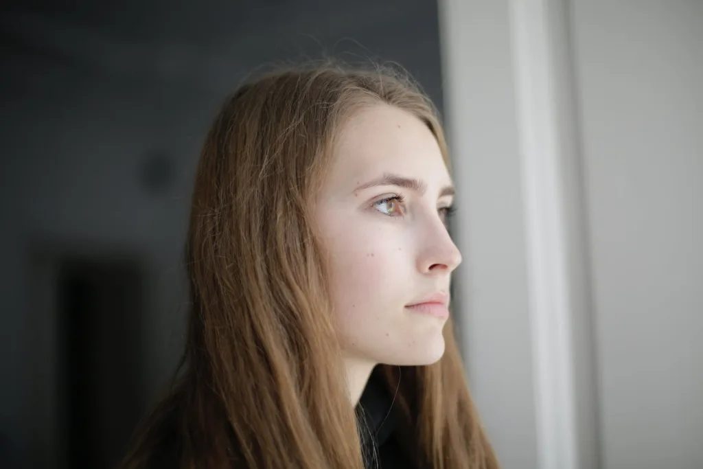 Pensive young woman in living room. Long-distance love, feelings of sadness. 