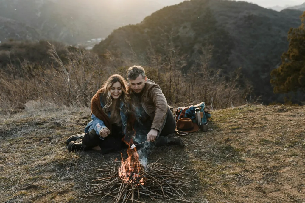 Man and Woman Grilling Marshmallows on Campfire in Mountains. Cultivating Passion, Shared experiences.