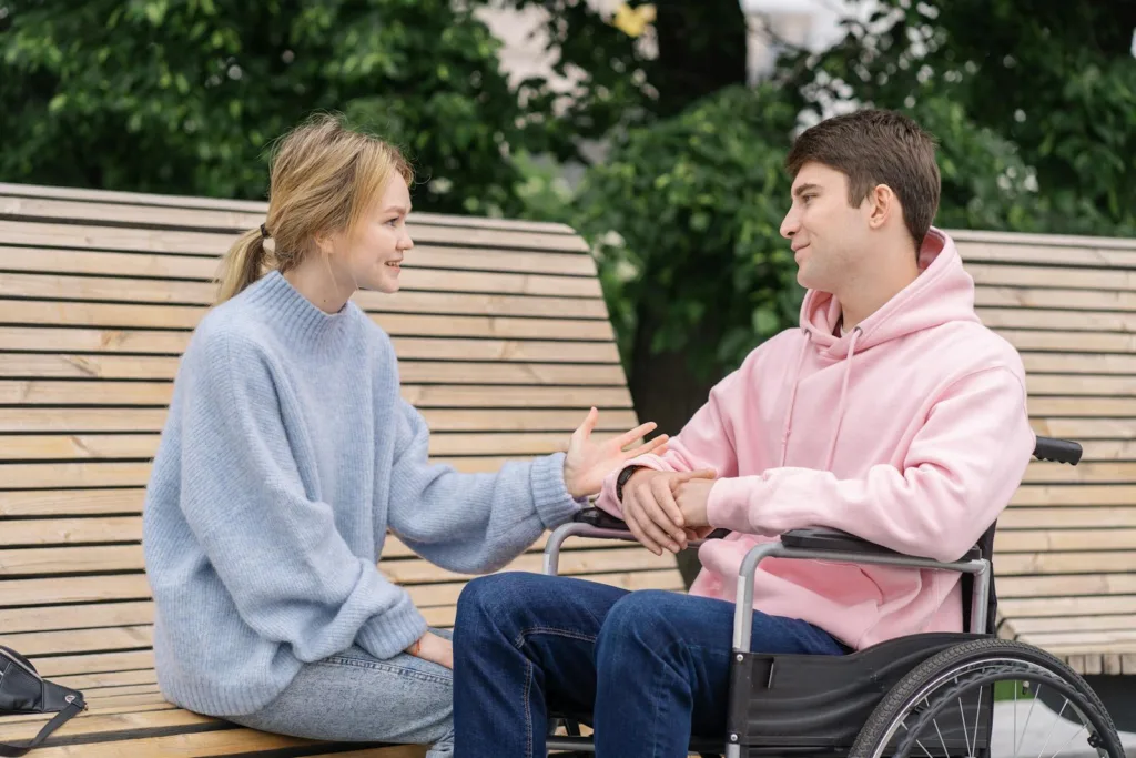 A Woman in Knitted Sweater Talking to the Man Sitting on the Wheelchair. Conflict Resolution, romantic relationship