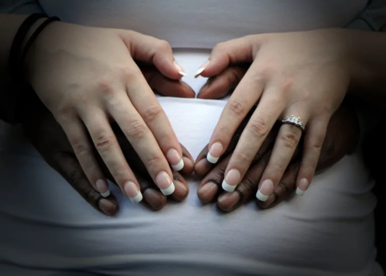 a couple with hands on a stomach. Interracial romance.