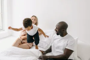 Happy Family with Child Playing in Bed. intercultural marriages