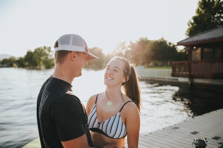 woman in white and black bikini top and white hat standing beside man in black shirt. understanding why he won't ask you out.