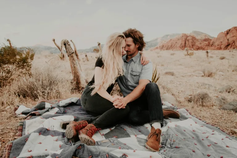 man and woman sitting on blanket while holding each other hands. rebuild trust after emotional infidelity