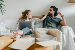 Girlfriend with laptop touching ethnic face of man on sofa. Overcoming Jealousy, Insecurity in a relationship.