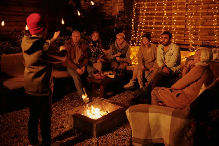 Boy acting out charade word while playing with friends and family around backyard bonfire at night. Cultivating passion, shared experiences