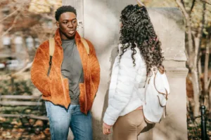 Excited couple in casual clothes leaning on stone border while talking and looking at each other. Dealing with jealousy, your love life.