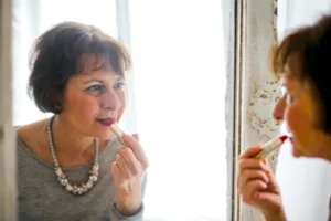 Photo of Older Woman Applying Lipstick In Front of the Mirror, older women, attracted to younger men